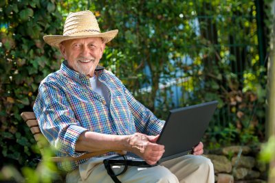 Ein alter Man mit Laptop auf dem Schoß