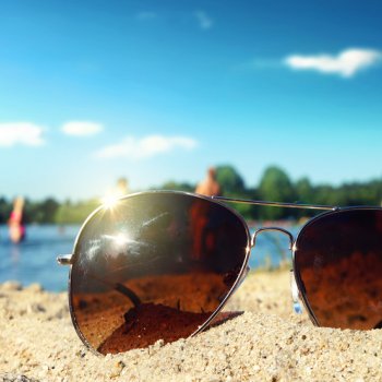 Eine Sonnenbrille liegt am Strand